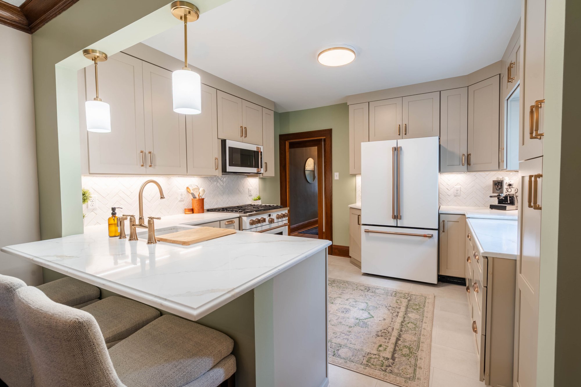 Remodeled kitchen with custom cabinetry, quartz countertops, peninsula seating, and herringbone tile backsplash.