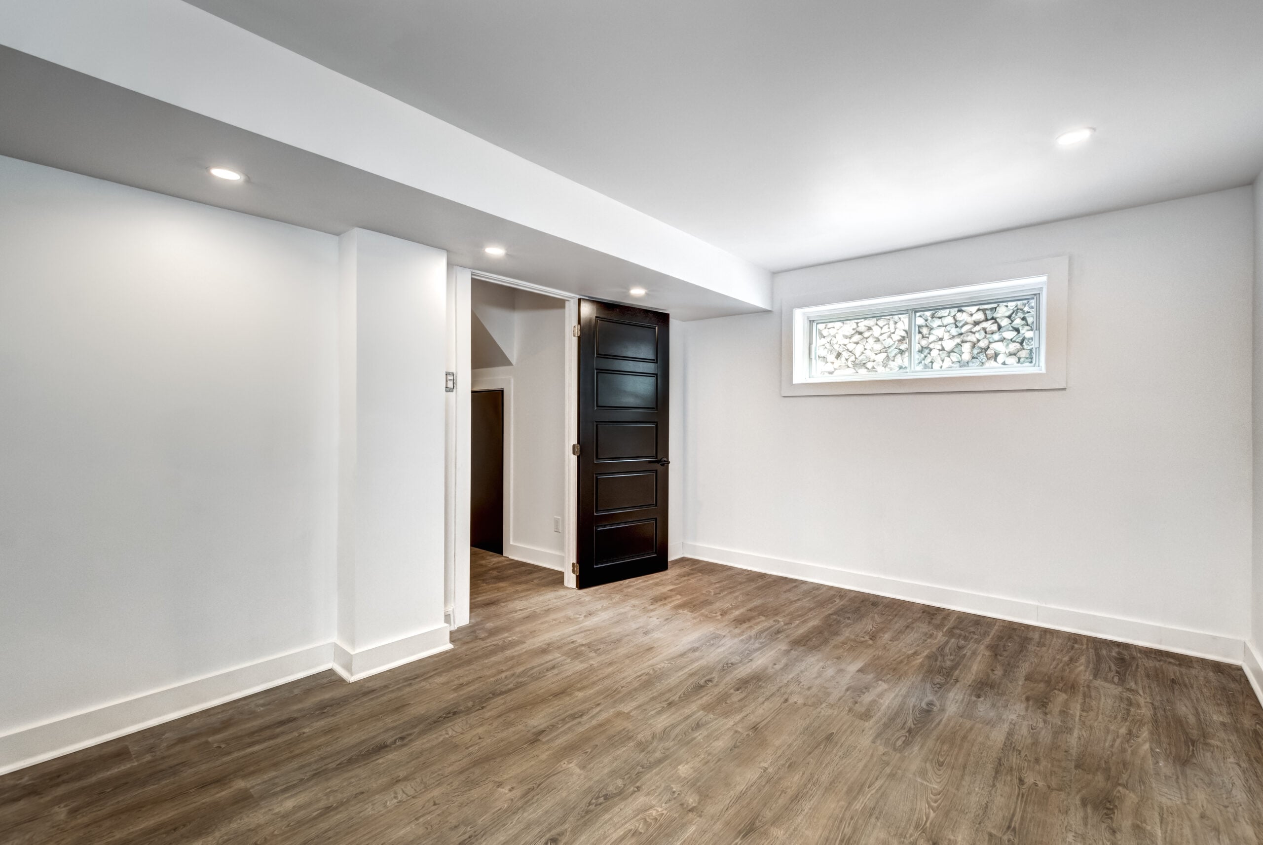 Room in finished basement with LVP flooring and glass block window