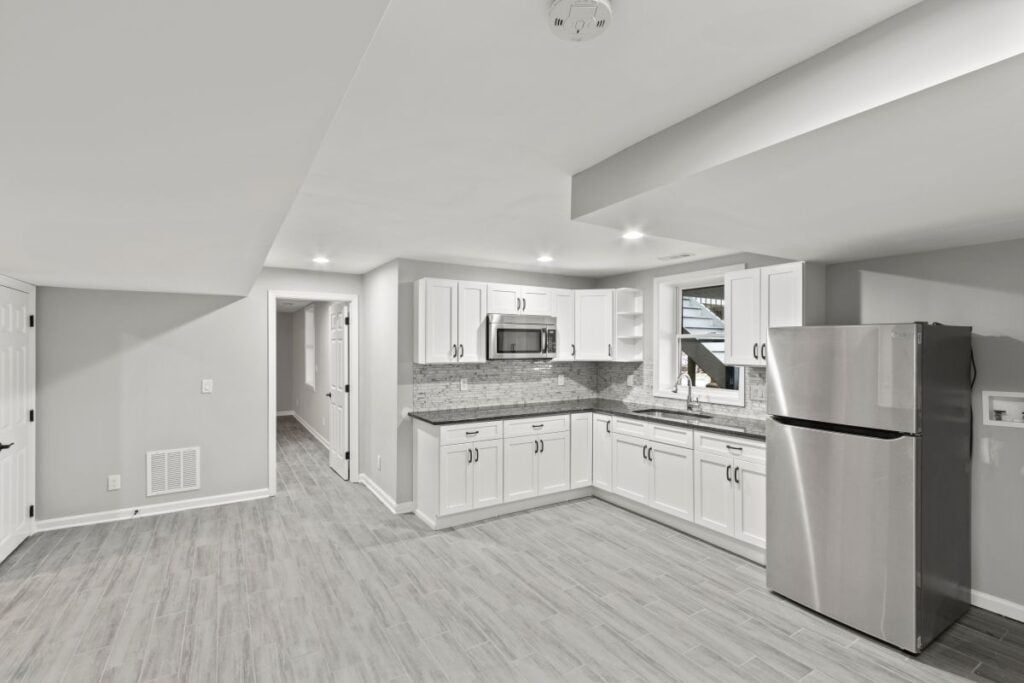 Finished basement kitchenette with white cabinetry, tile flooring and recessed lighting