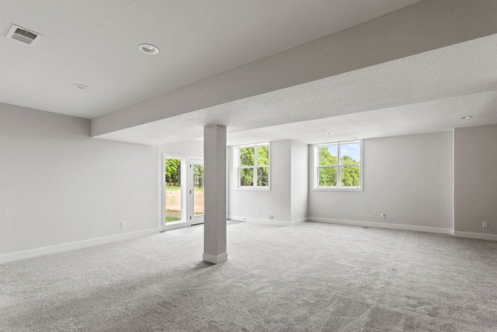 Spacious finished basement with painted walls, white trim, and light gray carpet
