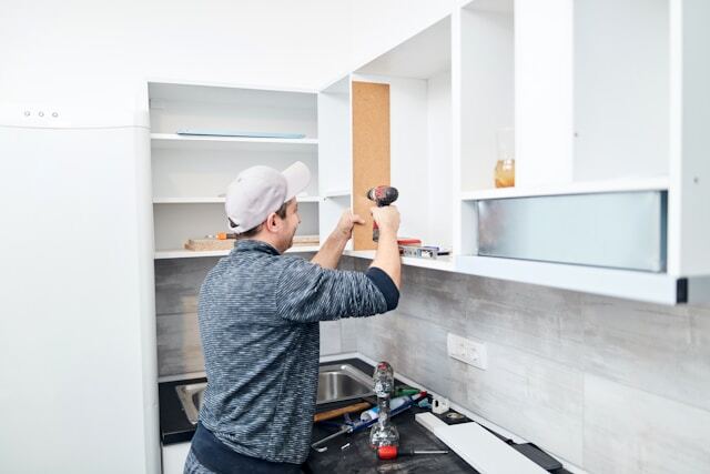 home remodeling contractor installing white kitchen cabinets during kitchen renovation