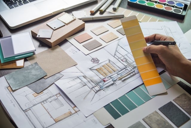 home remodel designer working on a hand drawn sketch with various material and color samples on table