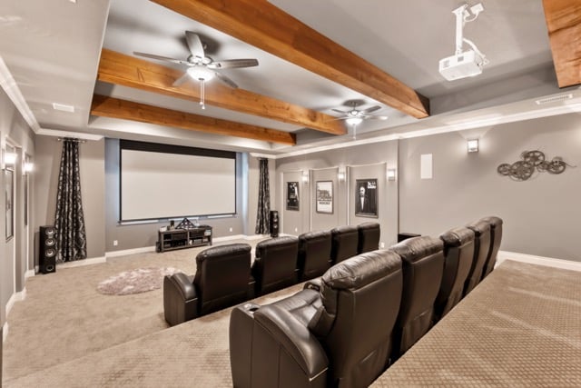at-home movie theater in basement with projector, tiered seating and wooden beams in ceiling