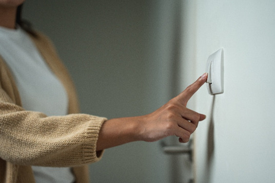 Person turning off a light switch on a wall in a home interior