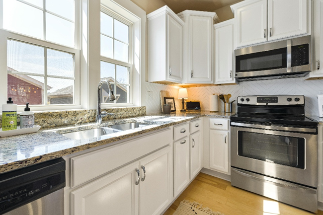 Bright white kitchen with granite countertops and white cabinetry