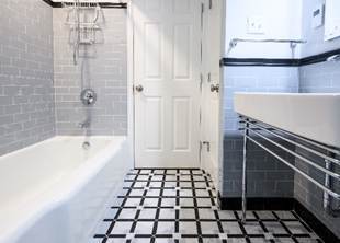 Remodeled bathroom with glossy subway tile and marble mosaic flooring
