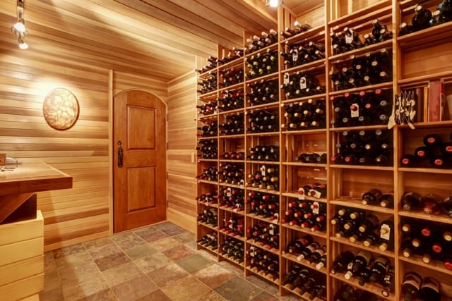 wine cellar in basement with wood paneling on walls and wood storage crates to store and display wine bottles