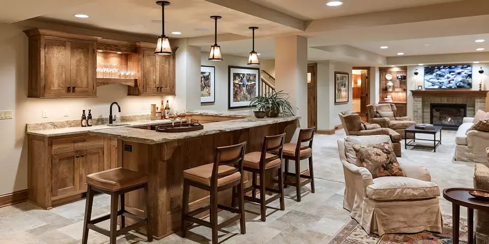 Finished basement with a built-in wet bar, wood cabinetry, bar seating, fireplace, and open living area.