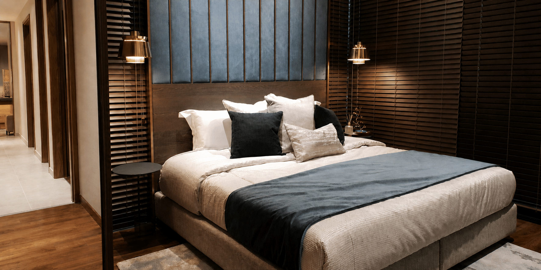 Cozy basement guest suite with warm wood finishes, layered bedding, pendant lighting, and dark accent walls.
