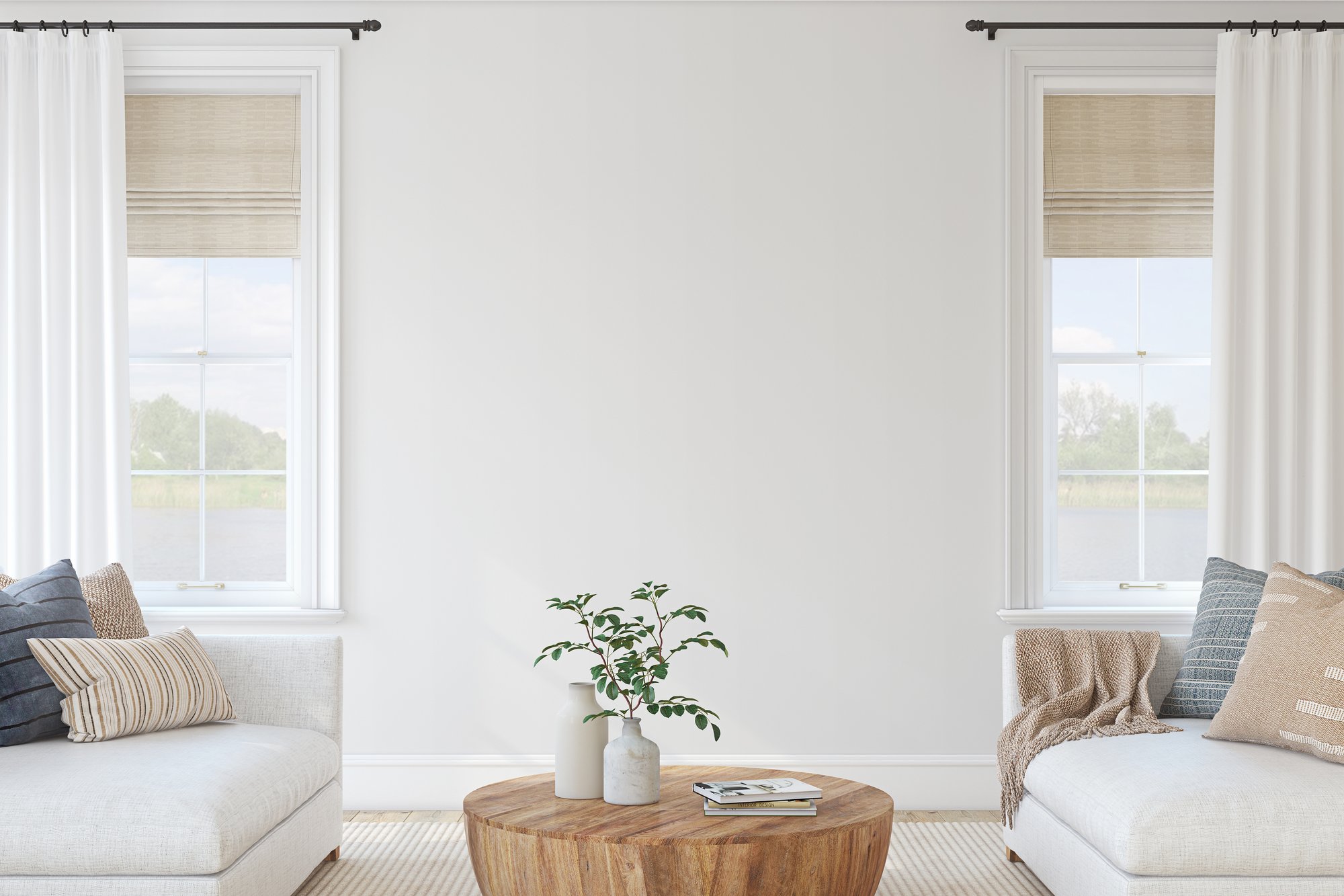 Bright living room with two white sofas, large windows, and a round wood coffee table.