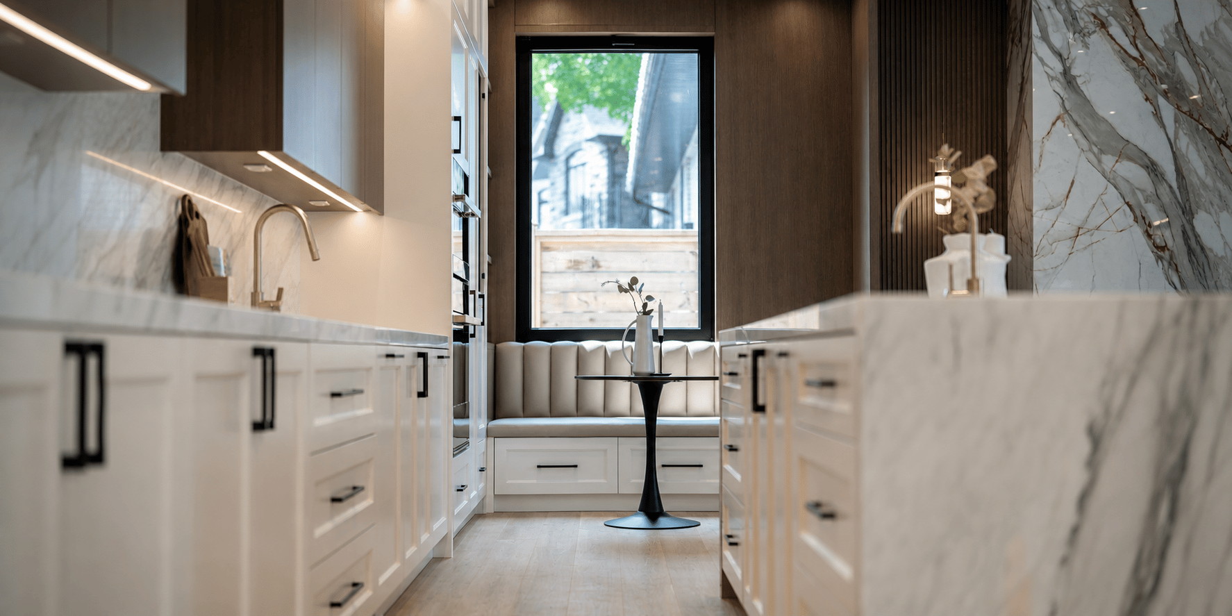 Modern kitchen with integrated under-cabinet lighting, recessed accent lighting, white cabinetry, marble surfaces, and dark wood details.
