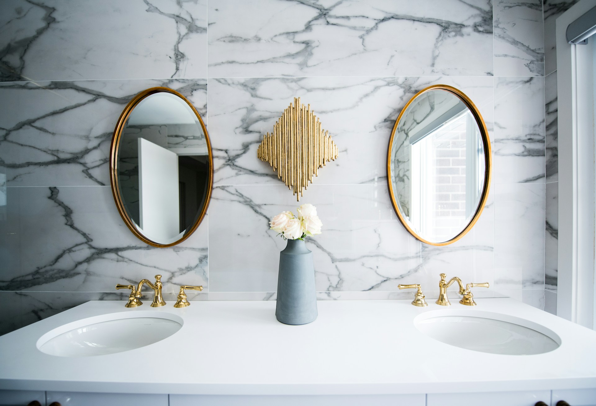 Bright marble and gold spa like bathroom with two sinks and two mirrors