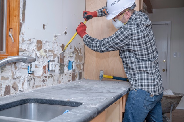 kitchen remodel worker removing kitchen backsplash tile during demolition phase
