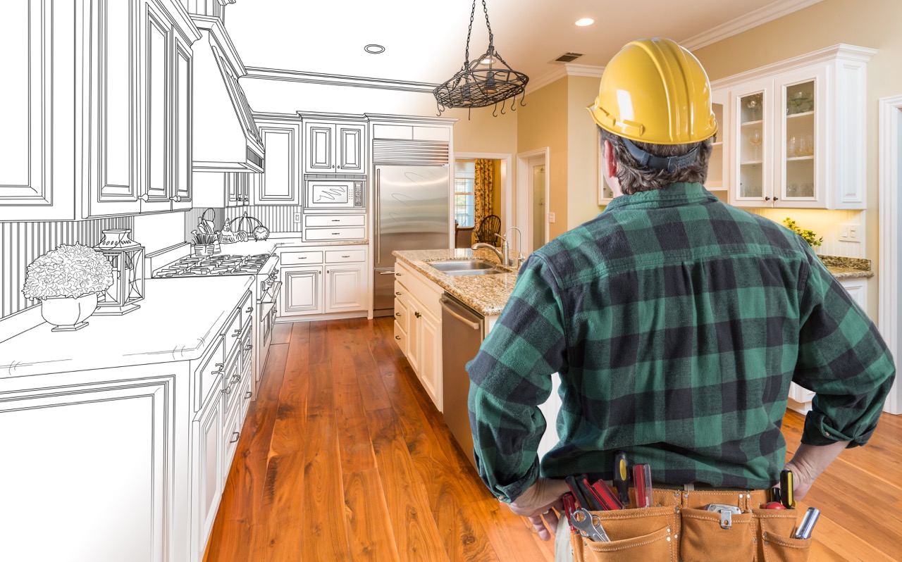 Male Home Remodeling Contractor with Hard Hat and Tool Belt Looking At Custom Kitchen Drawing Photo Combination On White