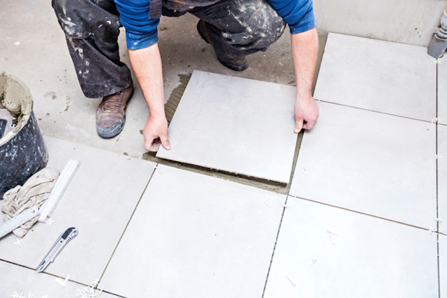 bathroom remodeling contractor installing large white tiles into bathroom during renovation project