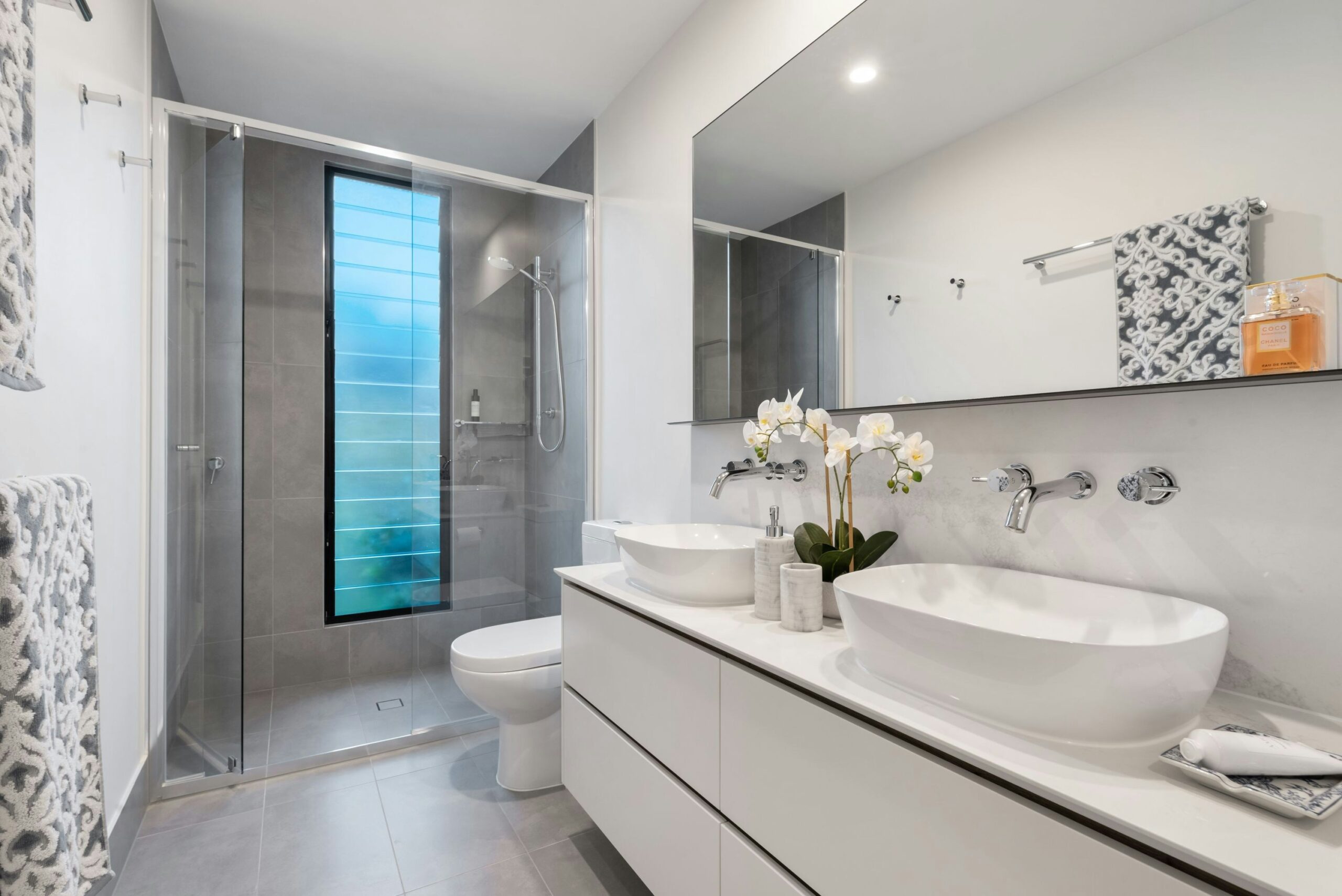 Remodeled bathroom with frameless glass shower, and tall frosted window