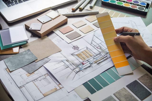 home remodel designer working on a hand drawn sketch with various material and color samples on table