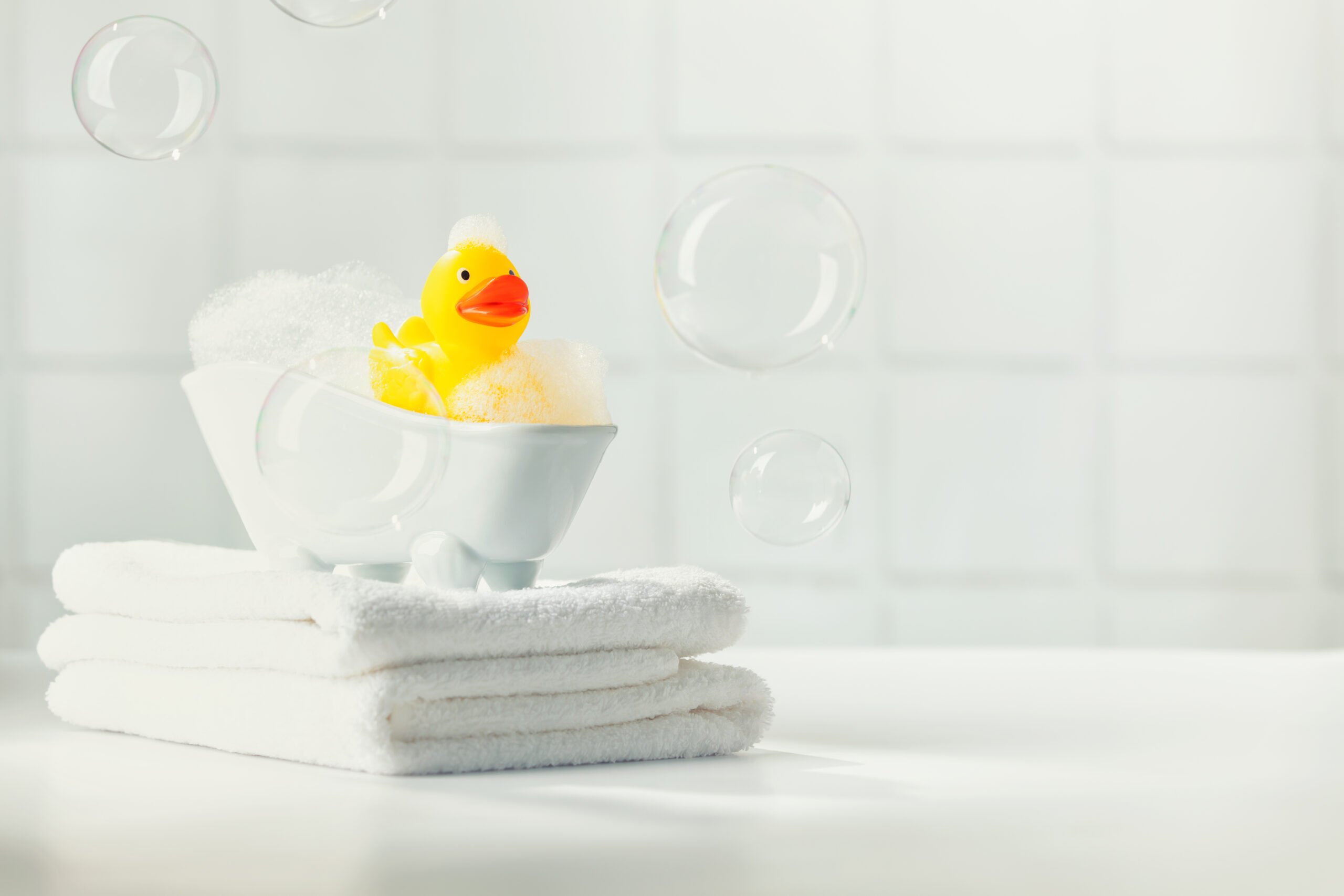 Rubber duck in miniature bubble bath in bathroom