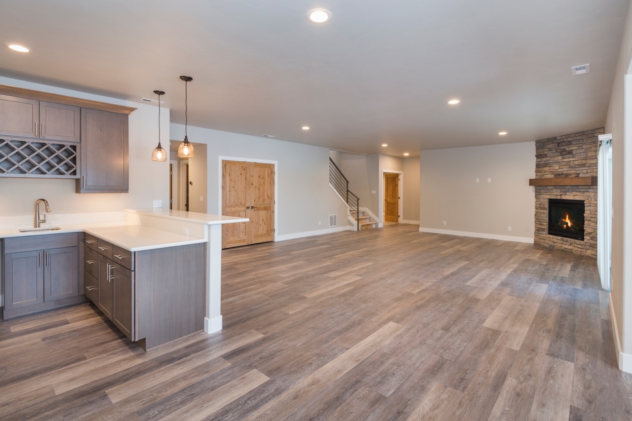 modern remodeled basement with hardwood floors, fireplace and kitchen area