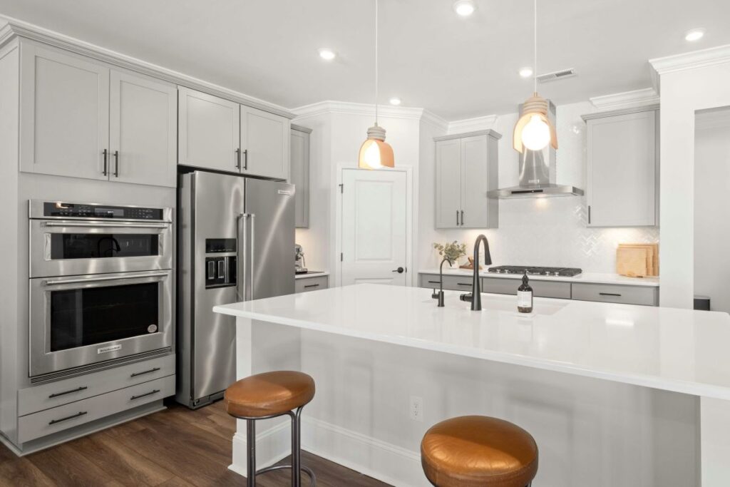 Modern bright kitchen with white island and stainless steel appliances.