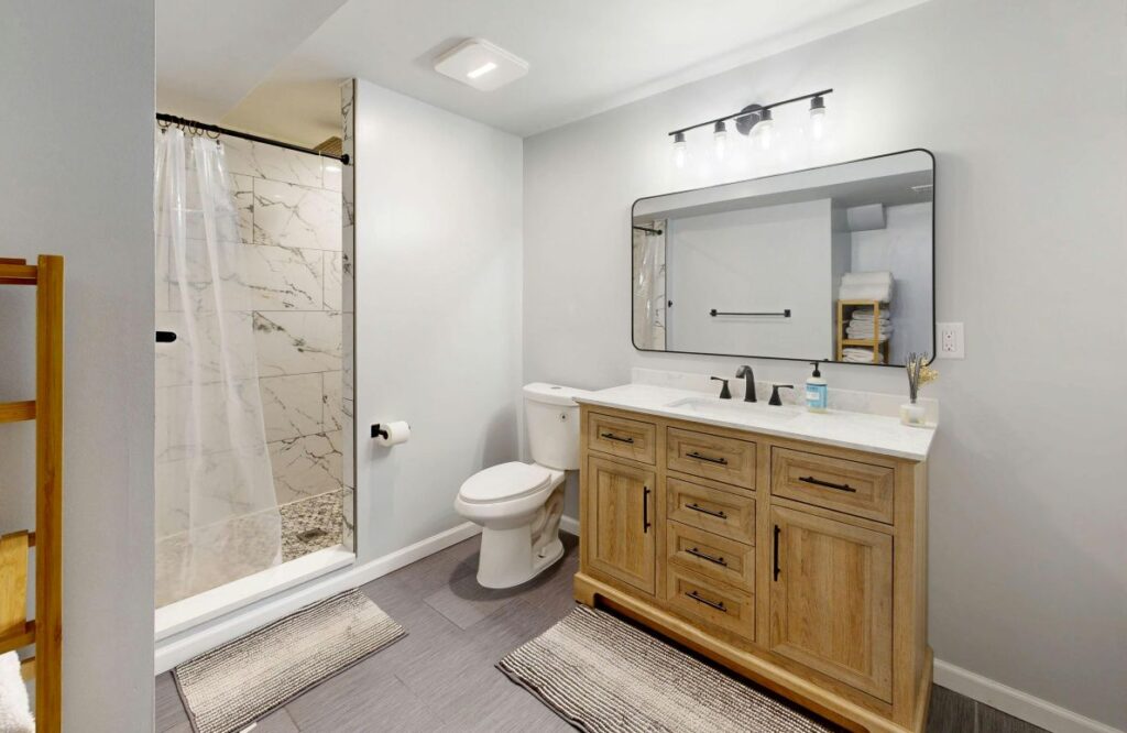 Modern bathroom remodel with wood vanity, white countertop, and tiled walk-in shower.