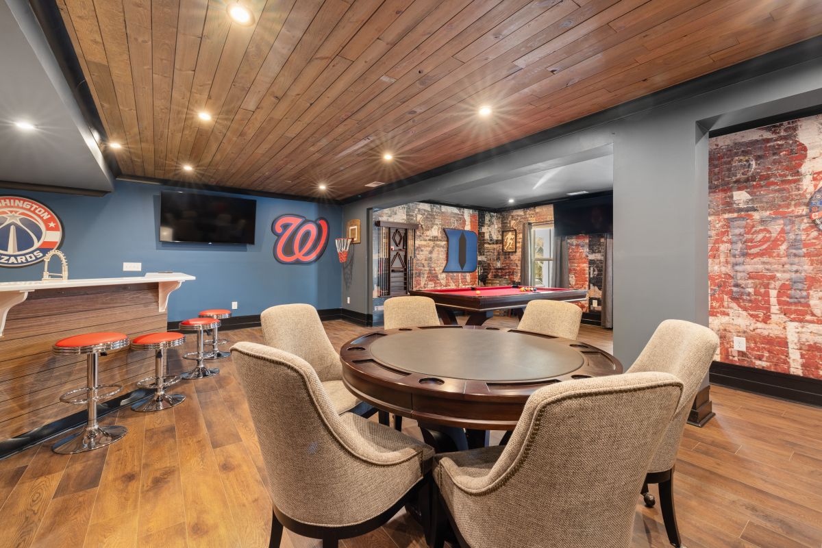 Finished basement with a custom bar, poker table, pool table, wood ceiling, and entertainment area.