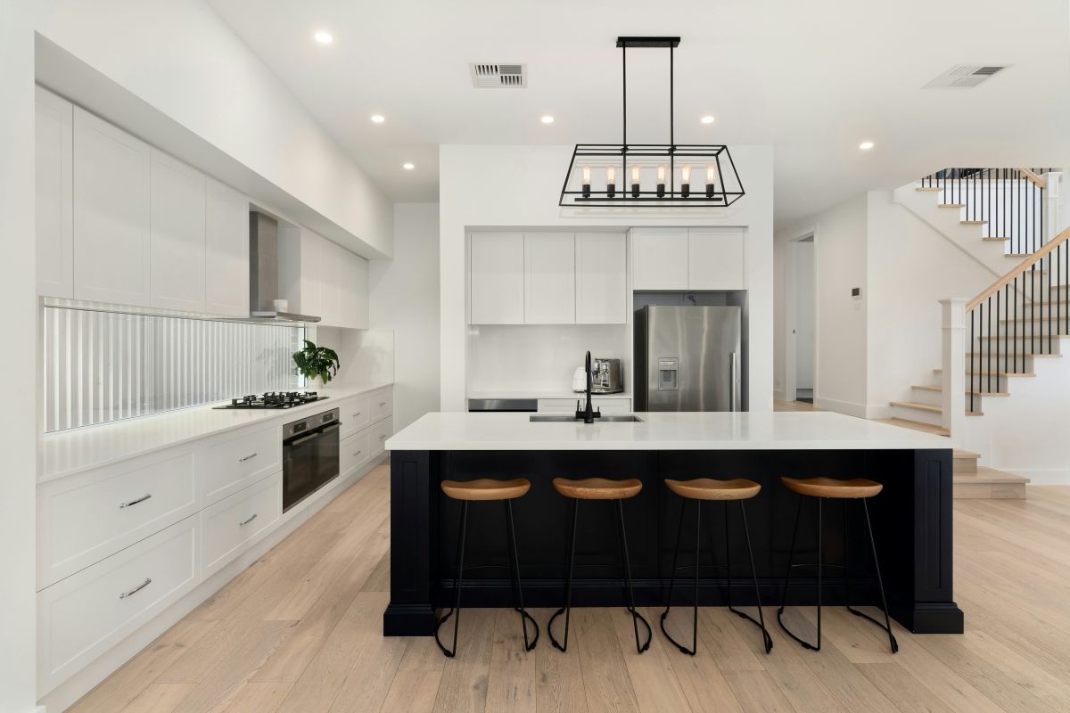 Modern kitchen with white cabinets, a black island, quartz countertops, stainless steel appliances, and pendant lighting.